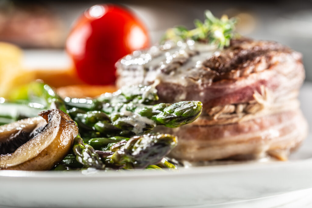 Grilled steak served on a plate with asparagus, potatoes and tomato.